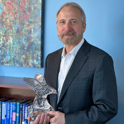 MITRE President and CEO Jason Providakes holding the Eagle Award