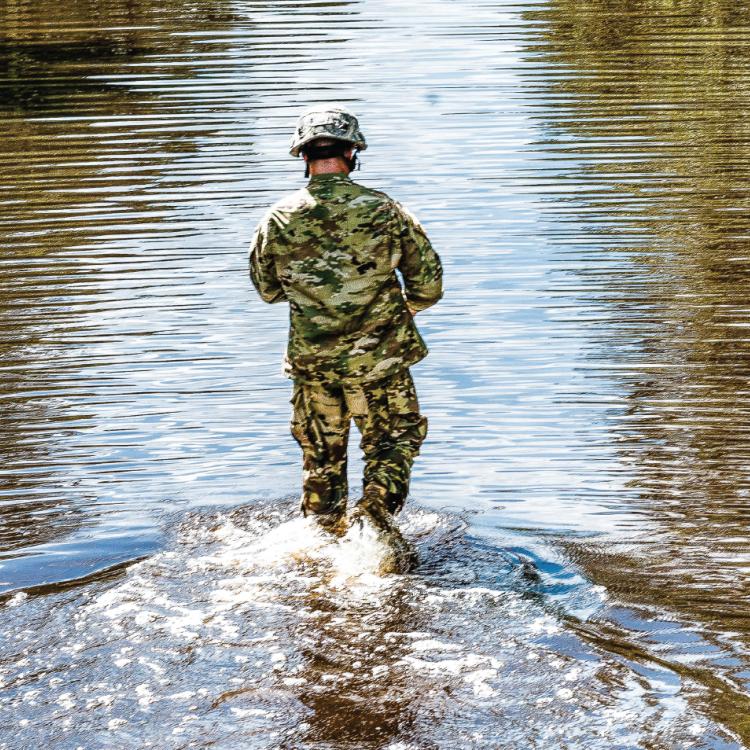 Person in uniform walking through flooded area