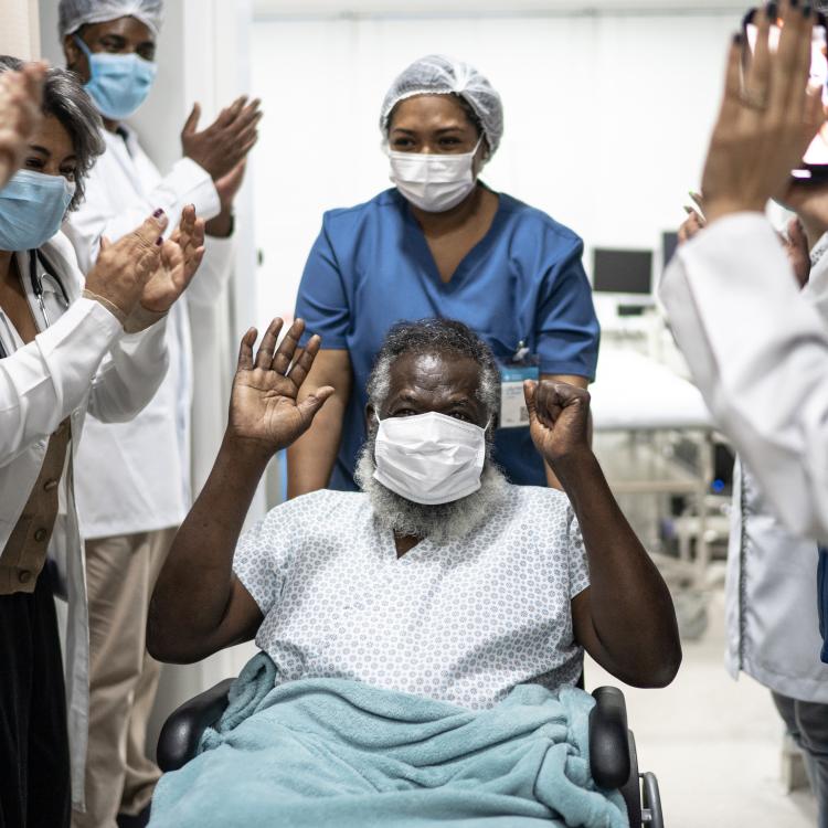 medical staff cheering patient in wheelchair