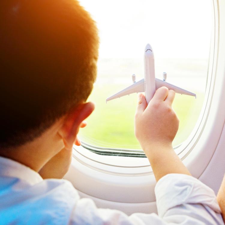 A child holding a toy plane and looking through a plane window